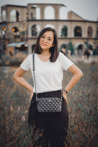 Portrait of young woman standing against plants