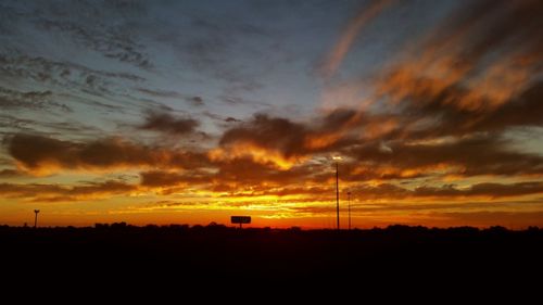 Silhouette electricity pylon against sky during sunset