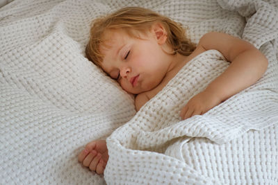 Portrait of cute baby boy sleeping on bed at home