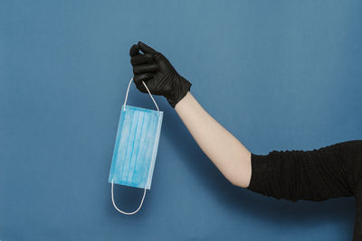 Close-up of hand holding umbrella against blue background