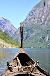 Wooden viking ship by fjord against mountain range