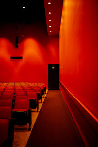 Bright red auditorium with empty chairs and exit sign