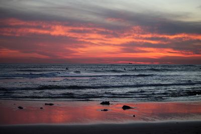 Scenic view of beach against cloudy sky during sunset