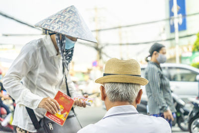 Rear view of people walking on road in city