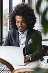 Young woman using mobile phone while sitting on table