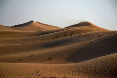 Sand dunes in desert against clear sky