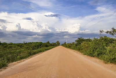 Road amidst field against sky