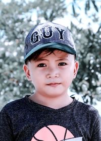 Close-up portrait of boy wearing cap against tree