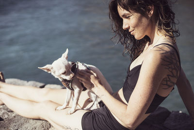 Midsection of woman with dog against water