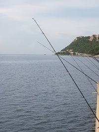 Fishing rod over sea against sky