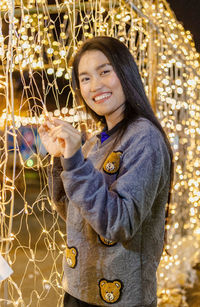 Portrait of young woman standing against christmas tree