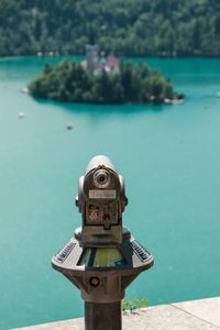 Close-up of coin-operated binoculars against lake