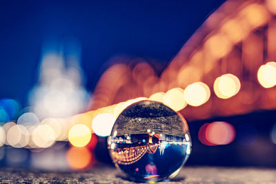Close-up of illuminated crystal ball in city against sky at night