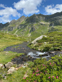 Scenic view of stream by mountains against sky