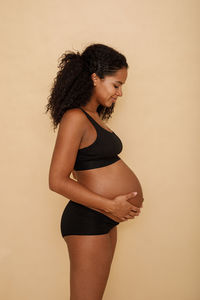 Side view of young woman standing against wall