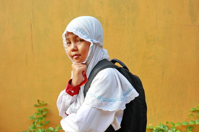 Side view of young woman looking away against wall