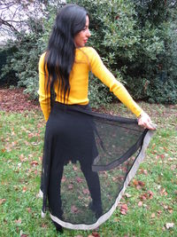 Young woman standing by tree