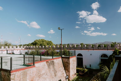 Bridge over canal by city against sky