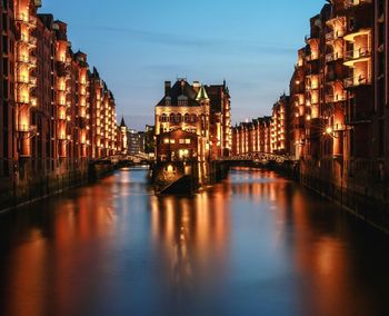 Illuminated buildings by river at night