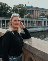 Portrait of smiling young woman standing against building