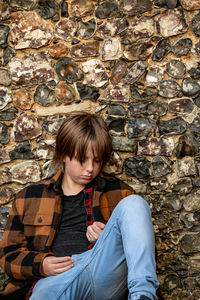 Portrait of young woman sitting on stone wall