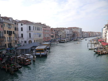 Boats in canal amidst buildings in city against sky