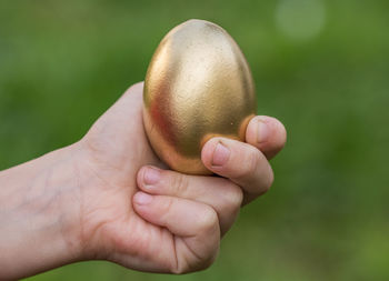 Cropped hand holding golden easter egg