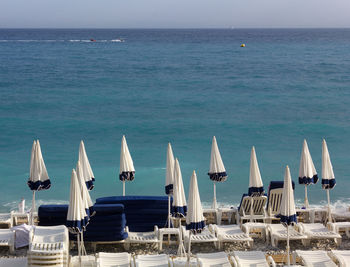 Lounge chairs and parasols on beach against sky