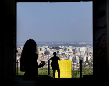 Rear view of silhouette people standing against cityscape