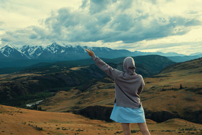 Rear view of man standing on mountain against sky