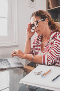 Young woman using mobile phone while sitting on table