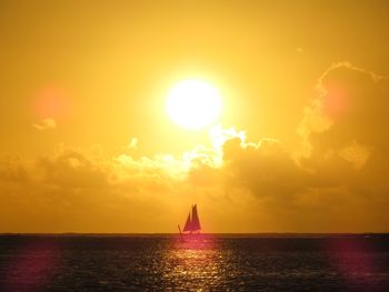 Silhouette sailboat sailing on sea against sky during sunset