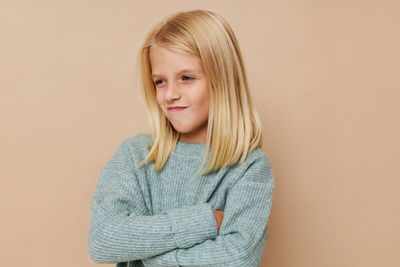 Portrait of smiling girl standing against gray background