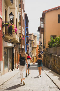 Rear view of women walking on street amidst buildings