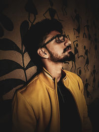 Portrait of young man standing against wall