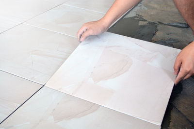 High angle view of person putting tile on floor