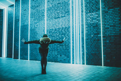 Full length of woman standing against illuminated lights on wall