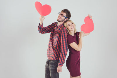 Young couple holding heart shape on white background