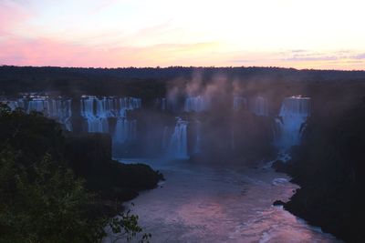 Scenic view of waterfall against sky during sunset