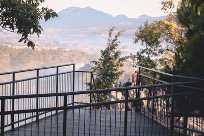 People standing on bridge against mountains