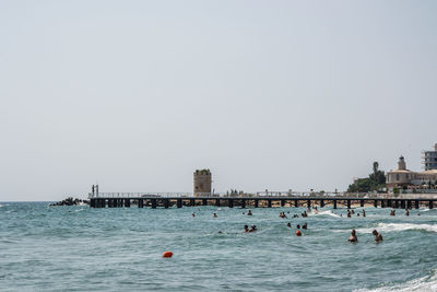 People swimming in sea against clear sky