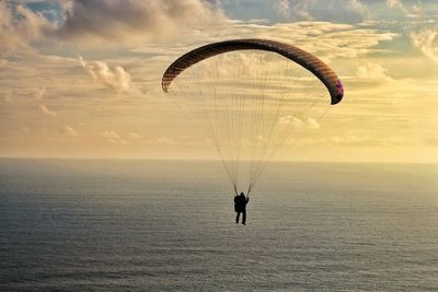 People paragliding over sea against sky