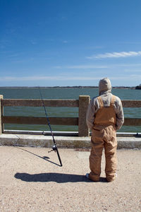 Rear view of man standing by sea against sky