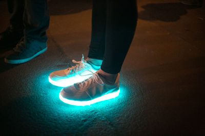 Low section of man standing on illuminated floor