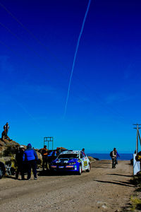 People on beach against clear blue sky