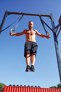 Low angle view of man jumping against sky