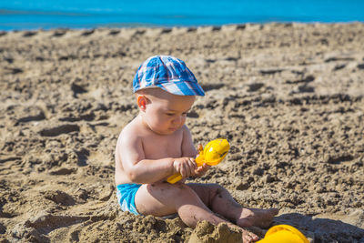 Boy playing with toys on sand at beach