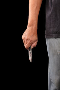 Midsection of man holding hands against black background