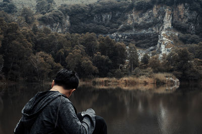  man sitting by lake against trees