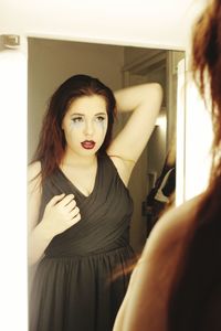 Young woman with smudged make-up reflecting in mirror